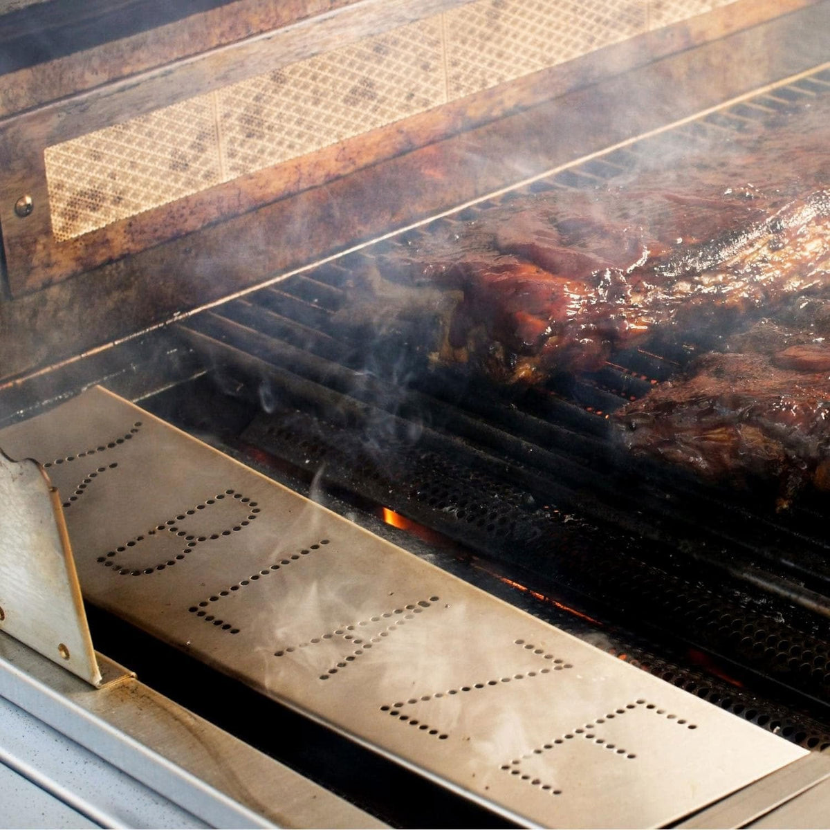 Stainless steel smoker box tray with wood chips on grill inside
