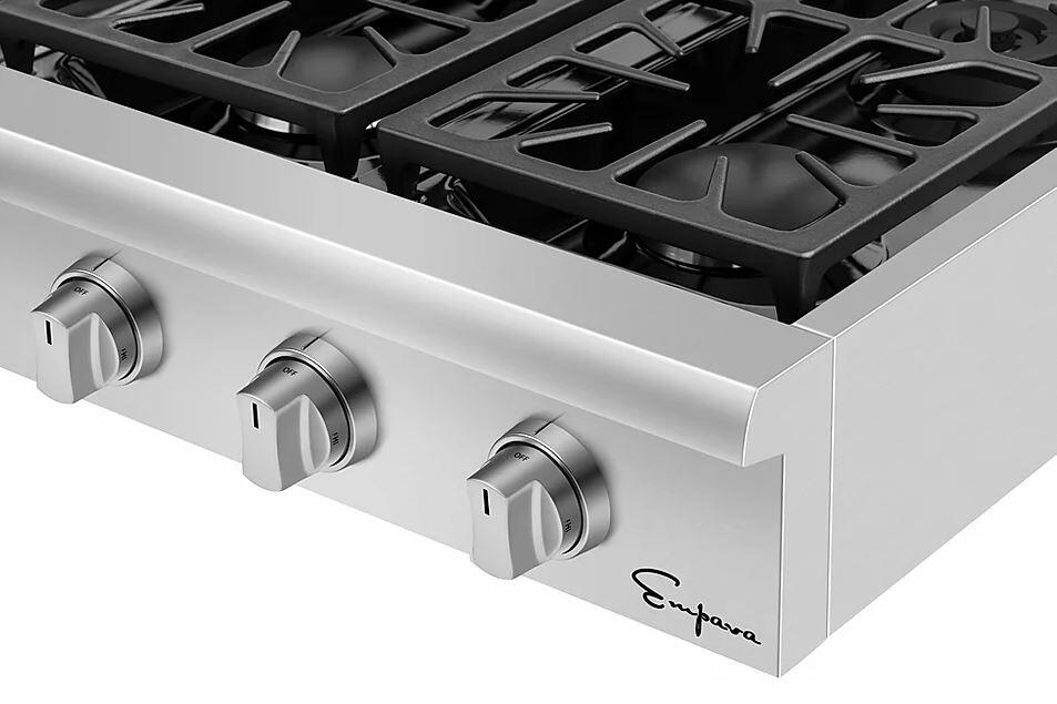 Close-up of stainless steel cooktop front with four control knobs and glossy metal burner grates