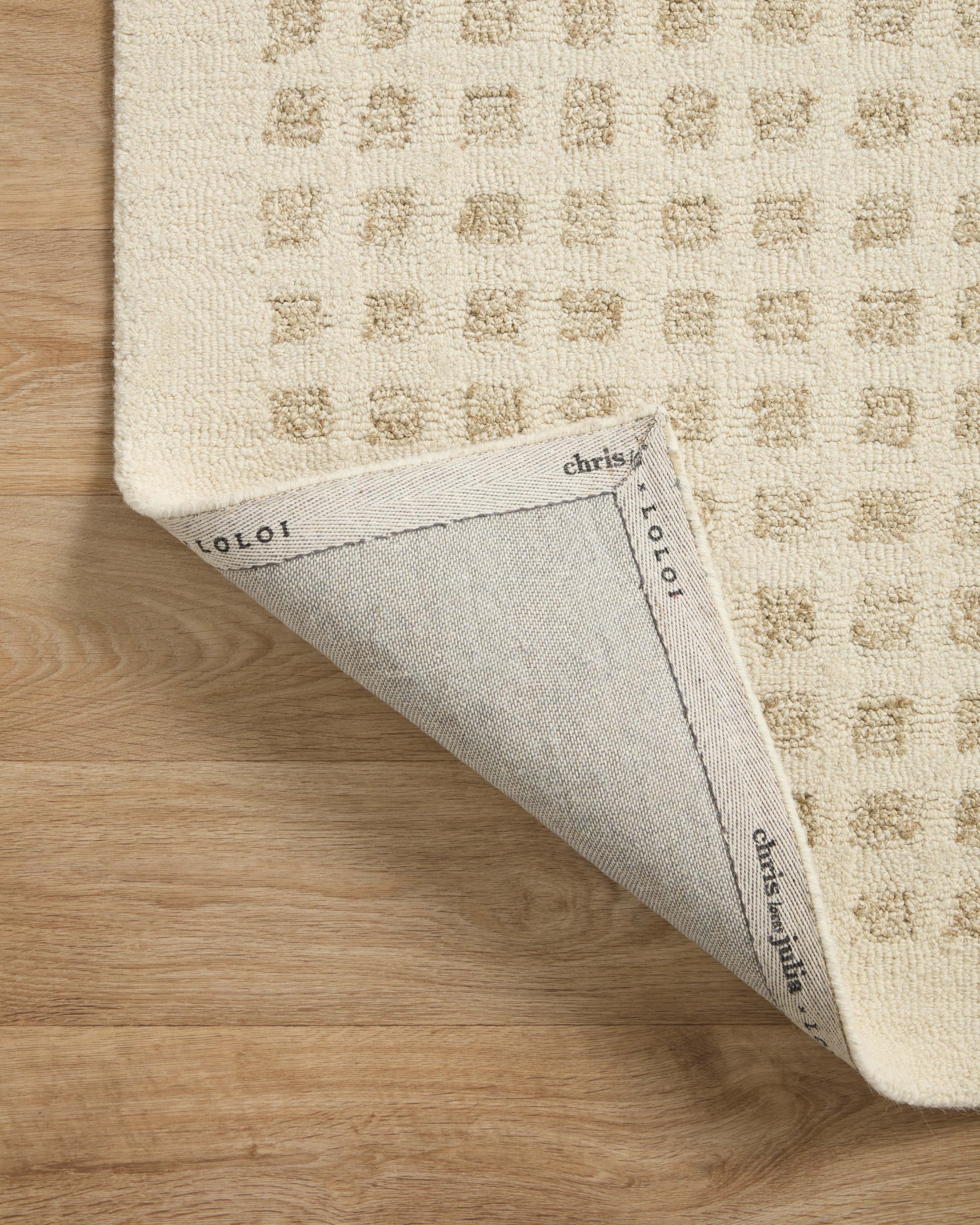 Ivory hand-tufted rug corner with stitched edge and brand labels