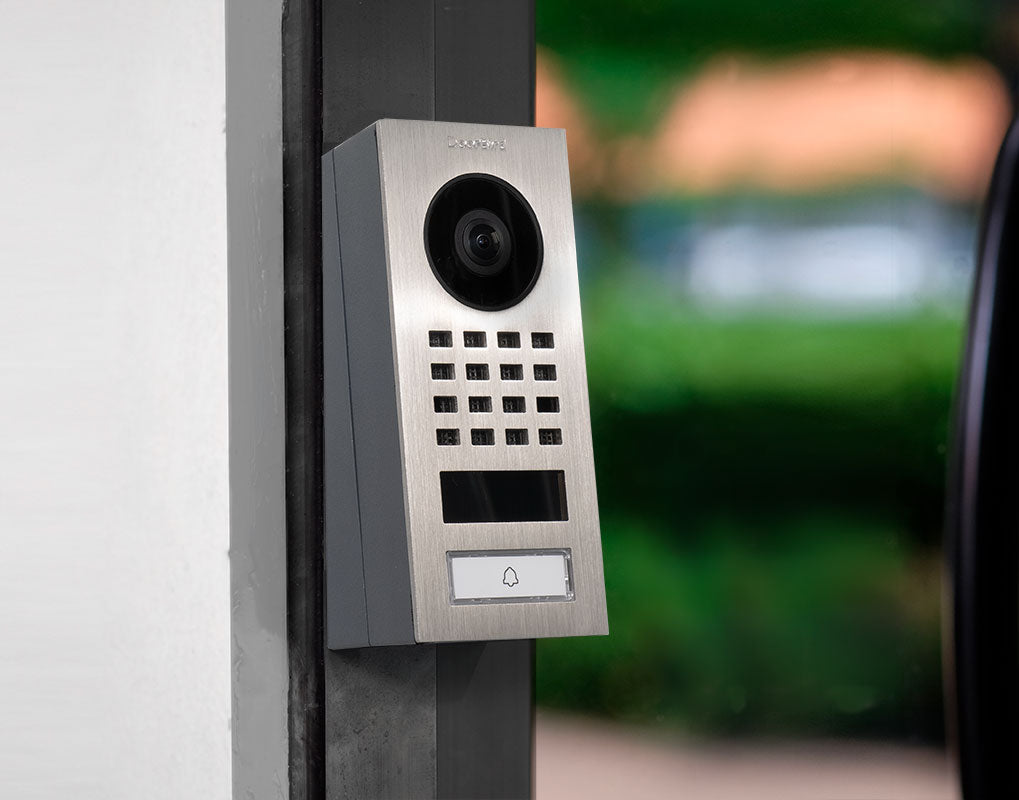 Wall-mounted corner adapter holding a door camera module with lens and keypad panel