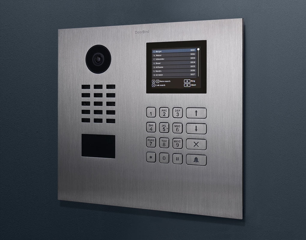 Stainless steel DoorBird IP video door station on wall with camera, screen, and keypad