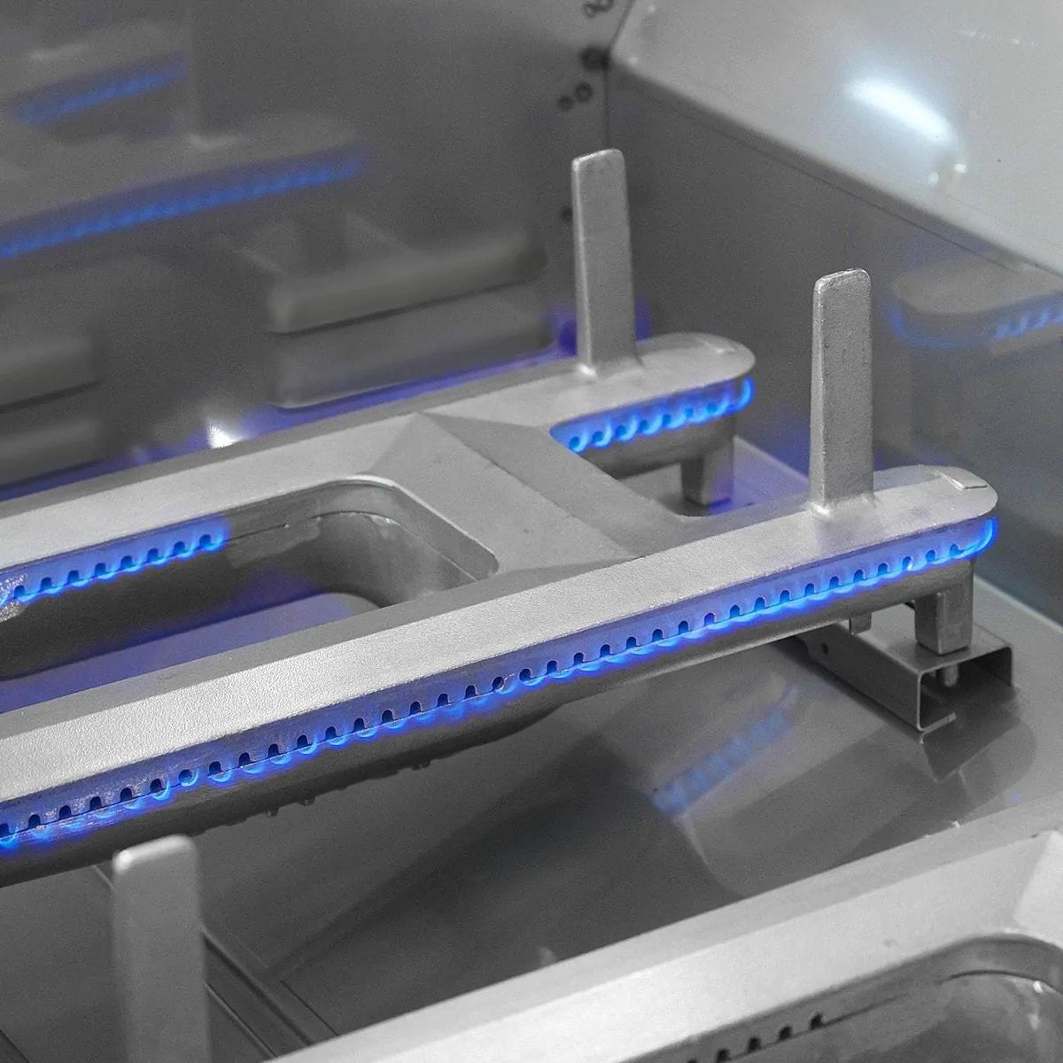 Built-in gas grill burner tubes with blue flame across the firebox