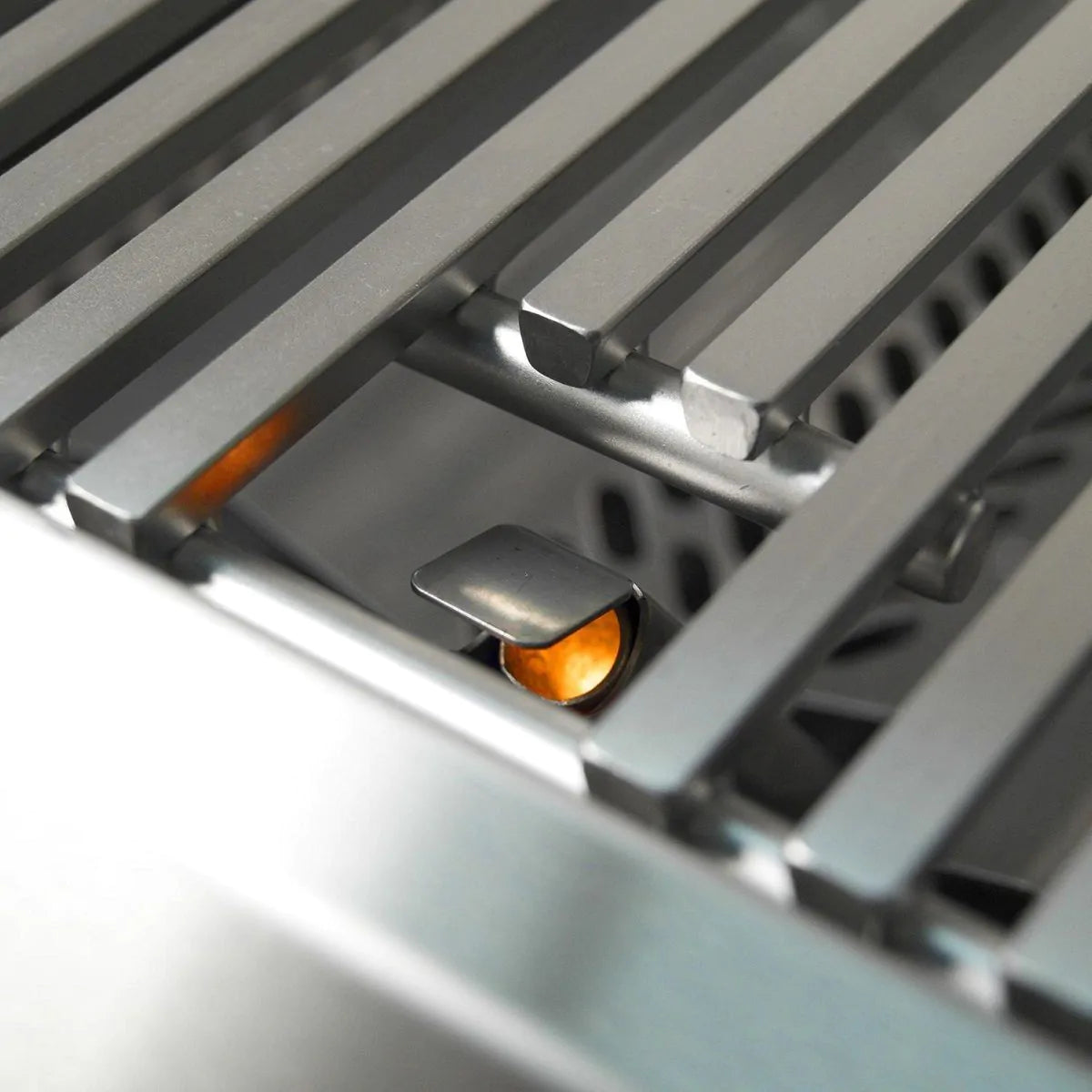 Infrared burner tray with glowing orange ignition at center inside stainless grill