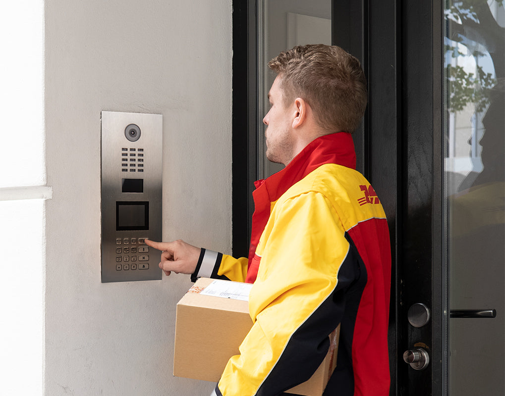 Delivery worker using stainless steel video door station keypad at entry door