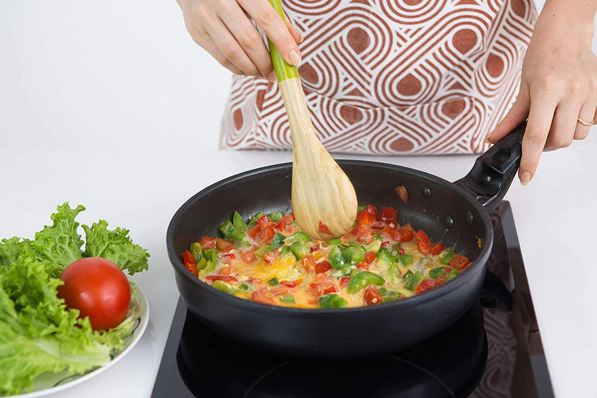 Portable induction cooktop with black glass top heating a skillet of vegetables