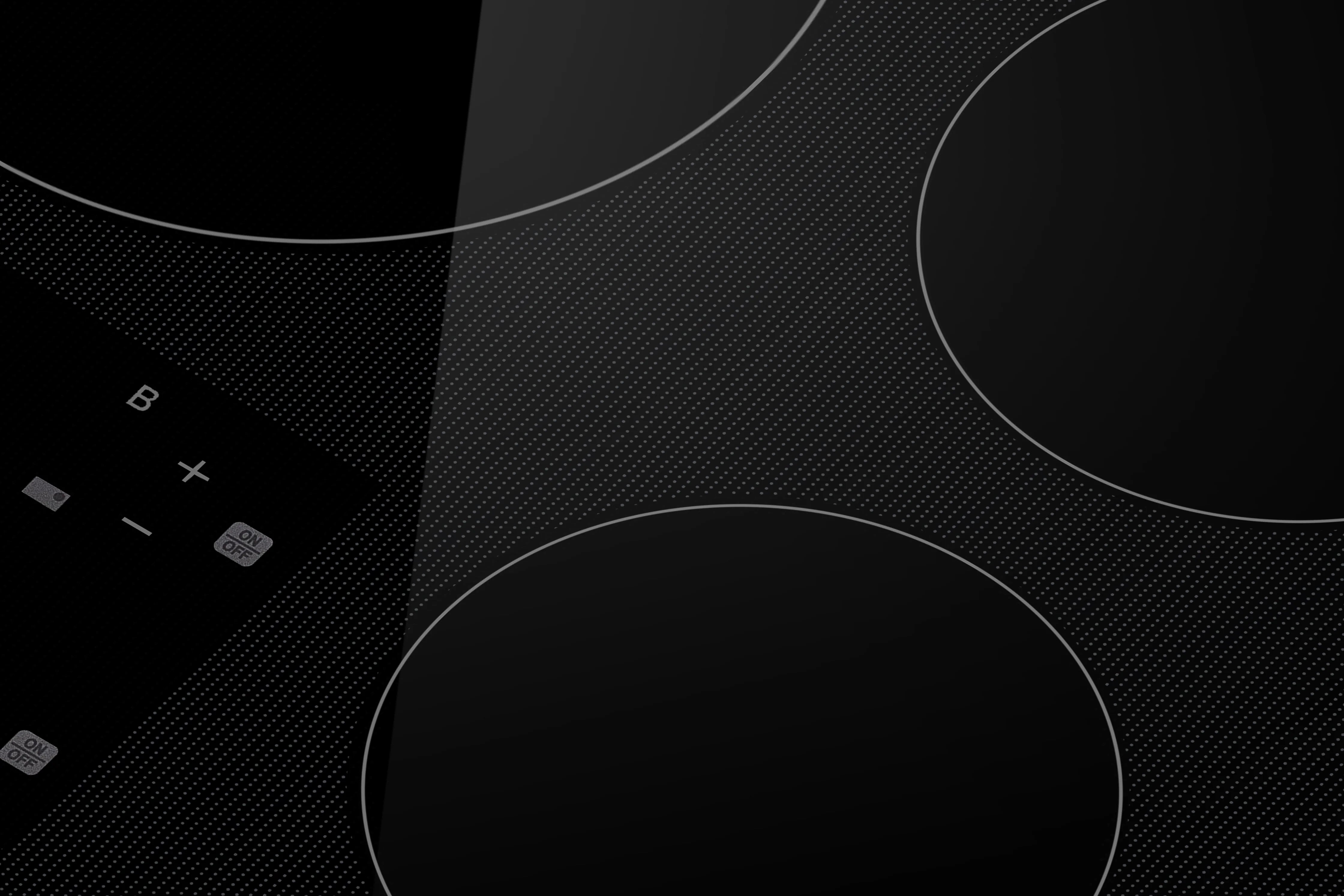 Black induction cooktop glass close-up with cook-zone circles and control icons