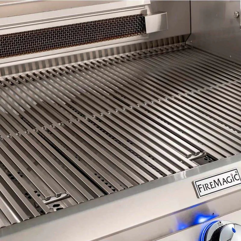 Stainless cooking grates with blue burner glow and FireMagic badge on front