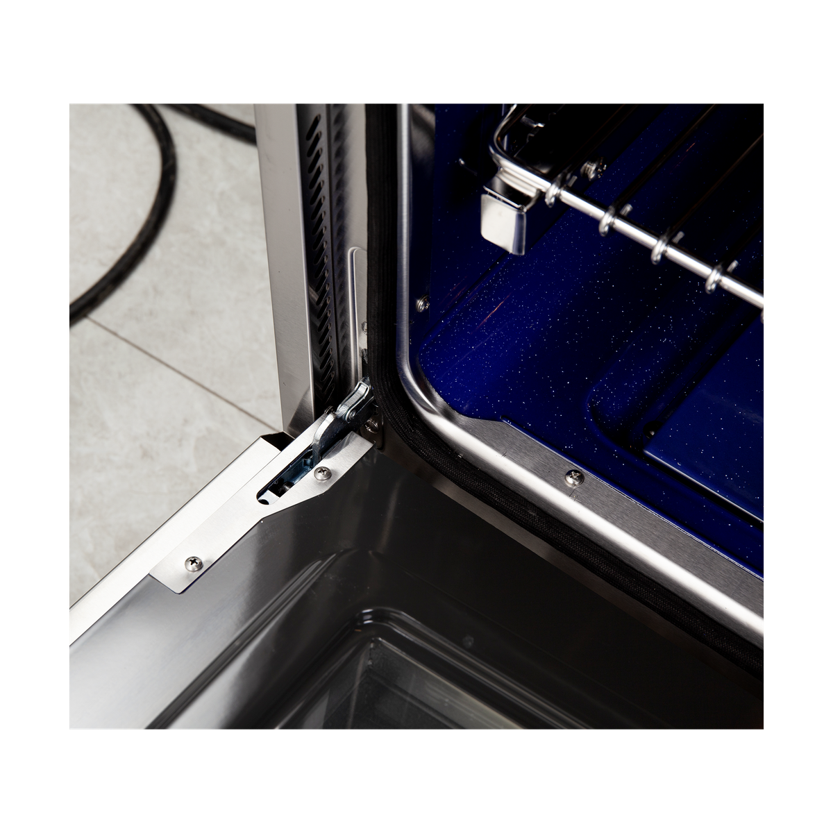 Stainless steel gas range oven door hinge with open dark interior and metal rails