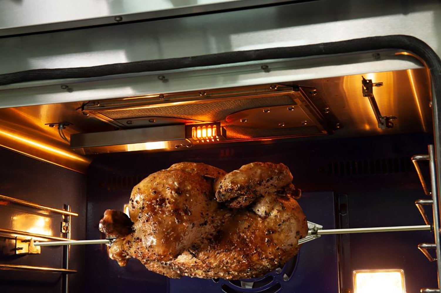 Gas oven cooking chamber with roasted chicken on an oven rack