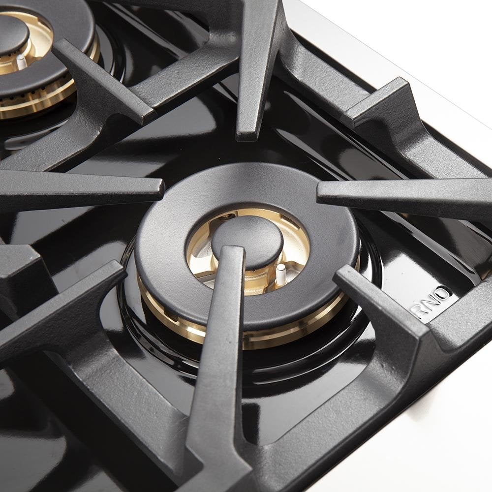 Close-up of gas cooktop burner with black grate and brass-style cap