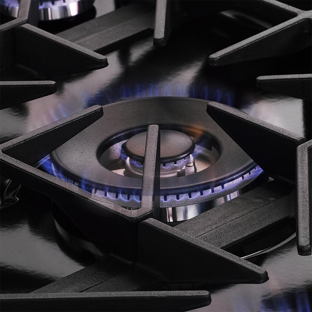 Gas range burner with blue flame under black grate, center burner detail