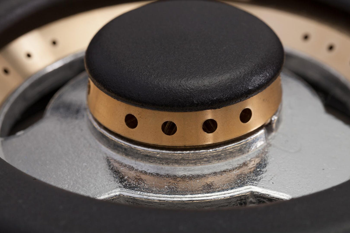 Dual-fuel range burner with black cap and bronze ring on silver surface