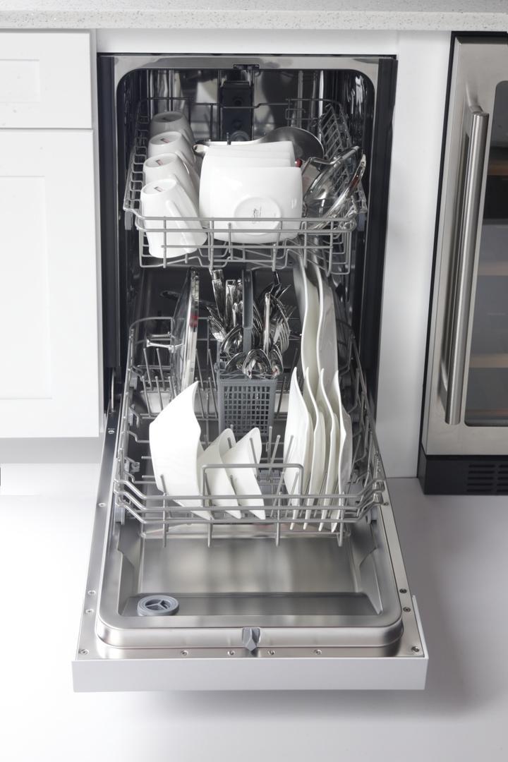 Dishwasher door open showing loaded racks and stainless steel interior tub