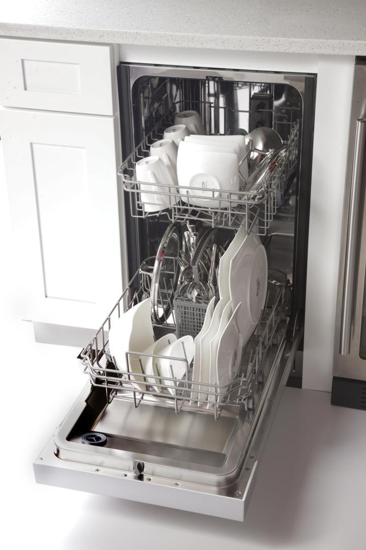 Open-front dishwasher with white dishware loaded in stainless steel racks