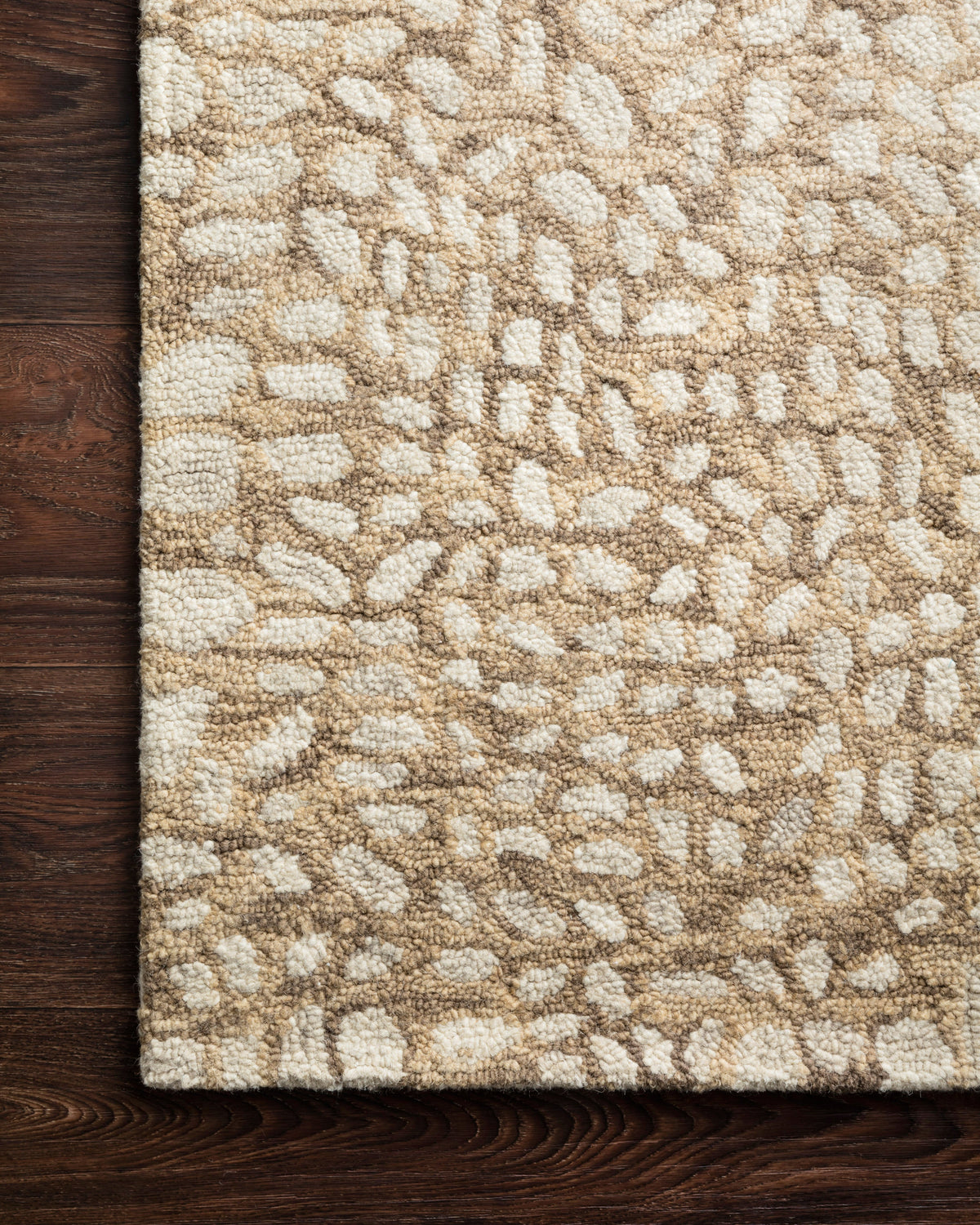 Neutral hooked rug corner with high-pile looped texture and mottled grid pattern