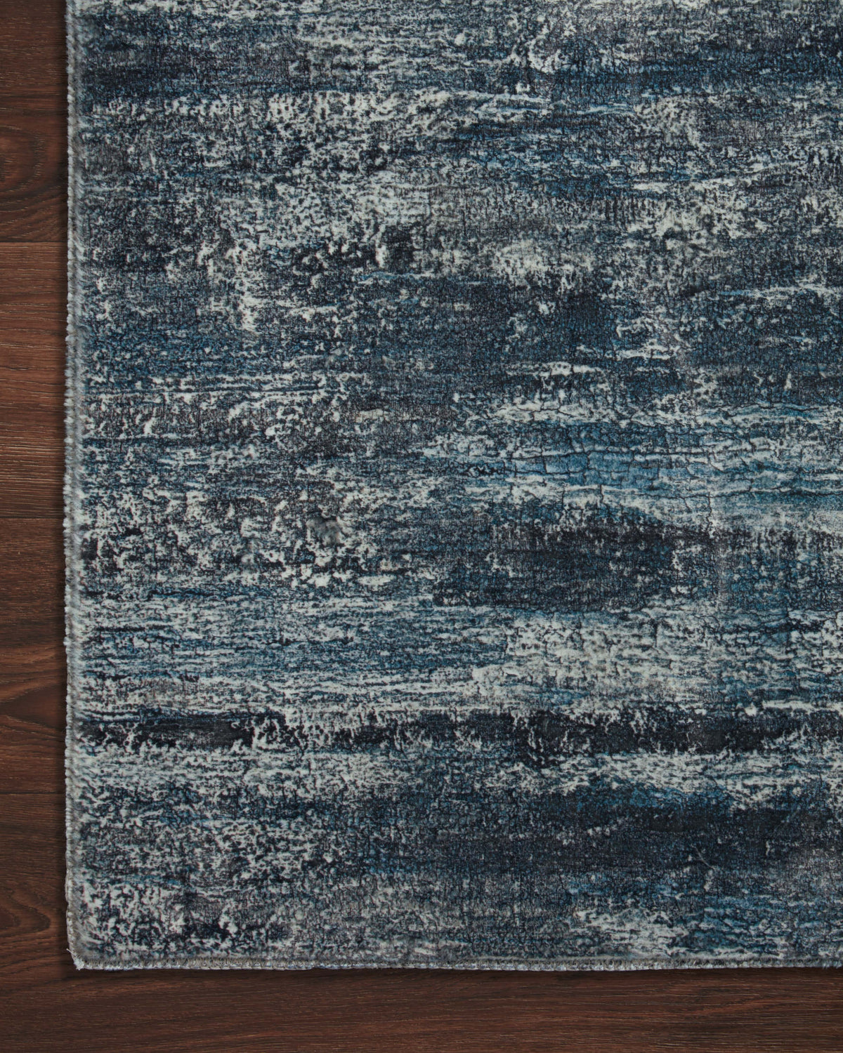 Hand-tufted area rug corner showing blue-gray distressed abstract texture