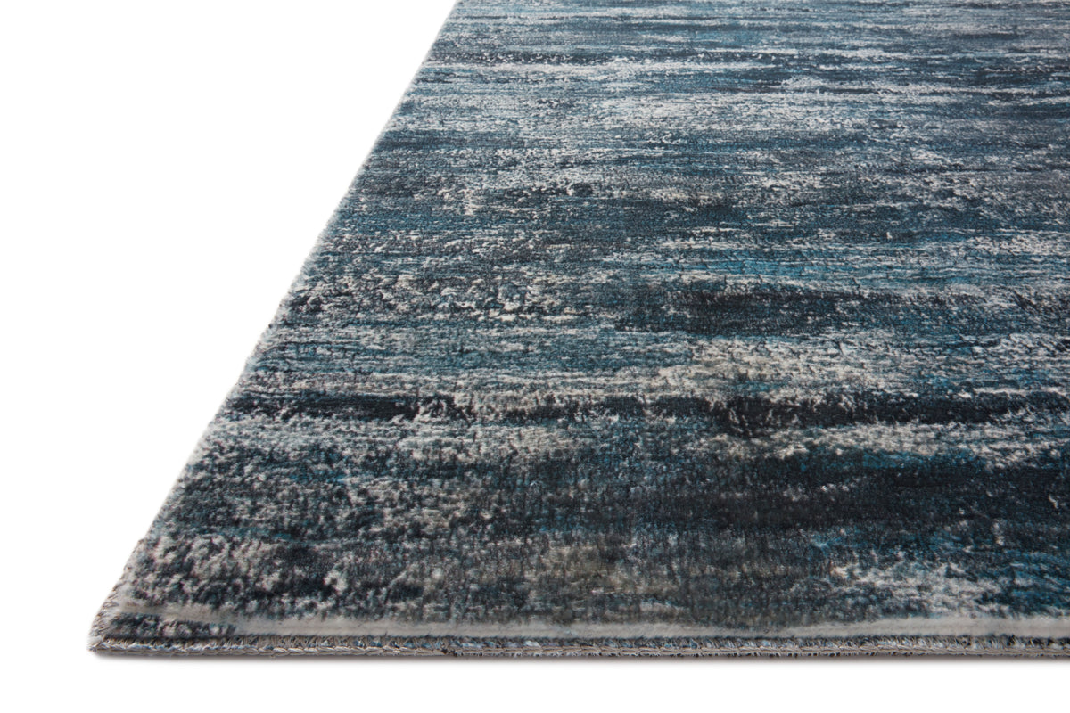 Blue and gray hand-tufted area rug corner with abstract horizontal stripe texture