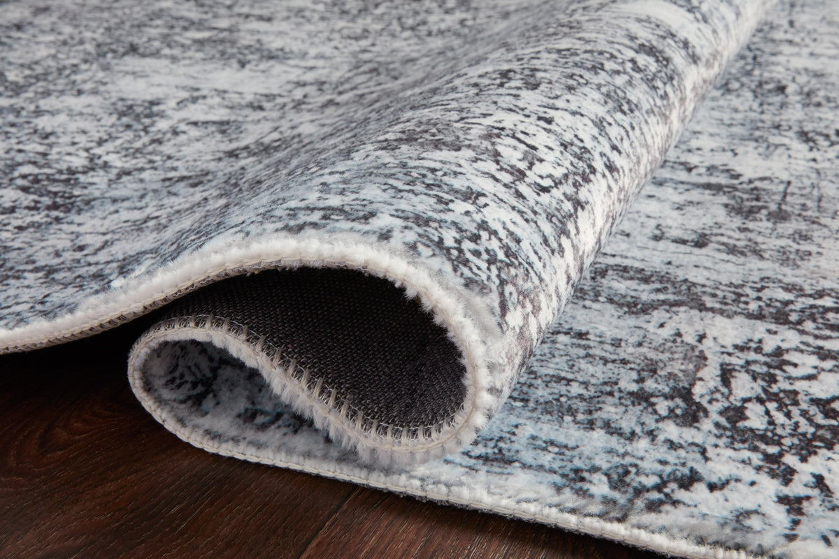 Hand-tufted rug edge with rolled pile and woven backing in gray and graphite tones
