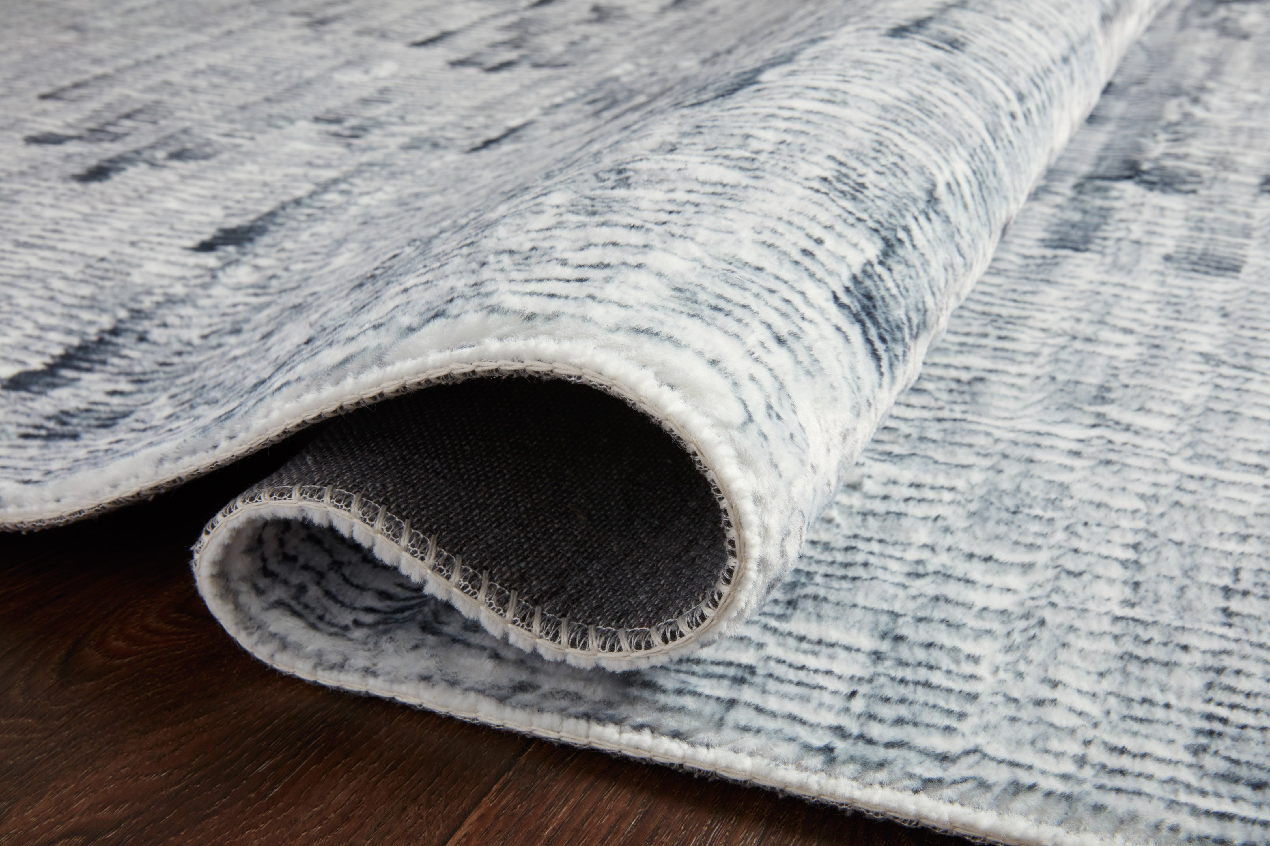 Silver and white rug edge with stitched border and short pile underside