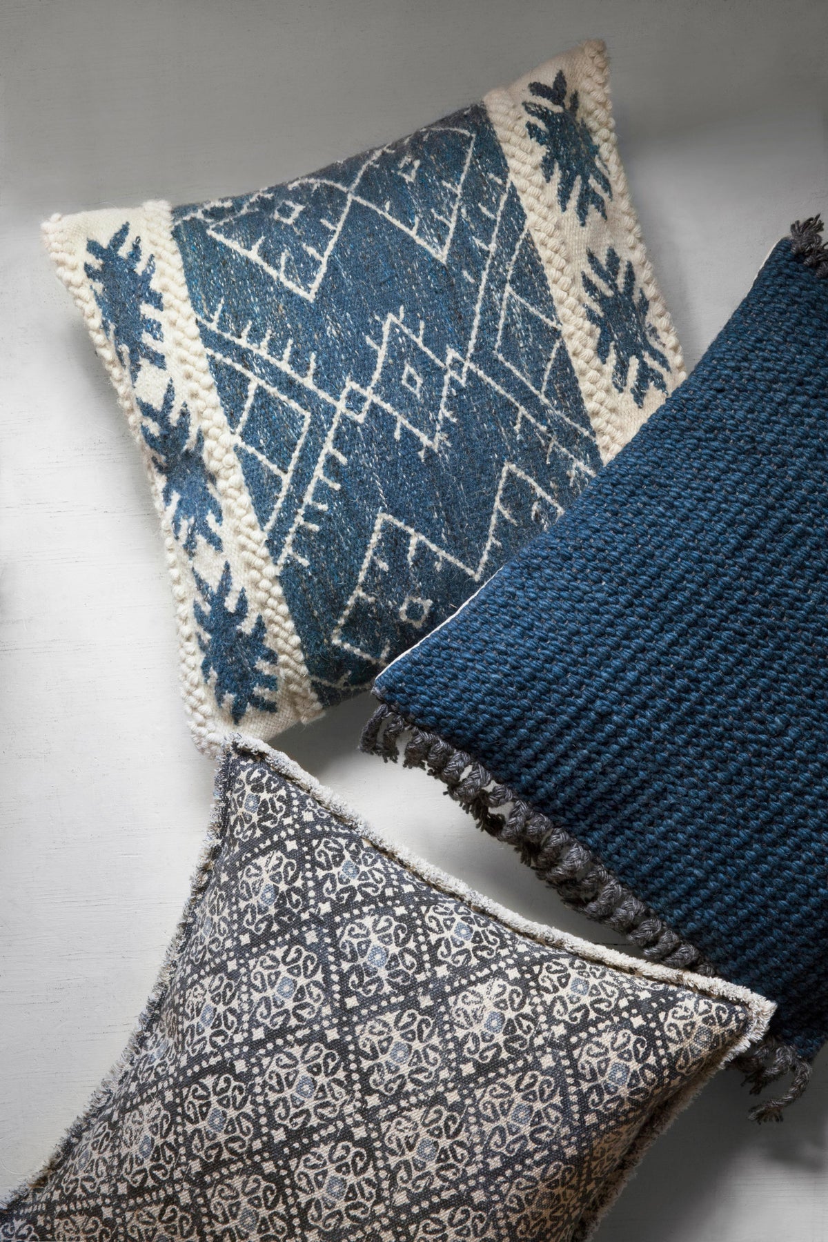 Decorative down-filled pillow with navy geometric pattern, off-white trim, and fringe