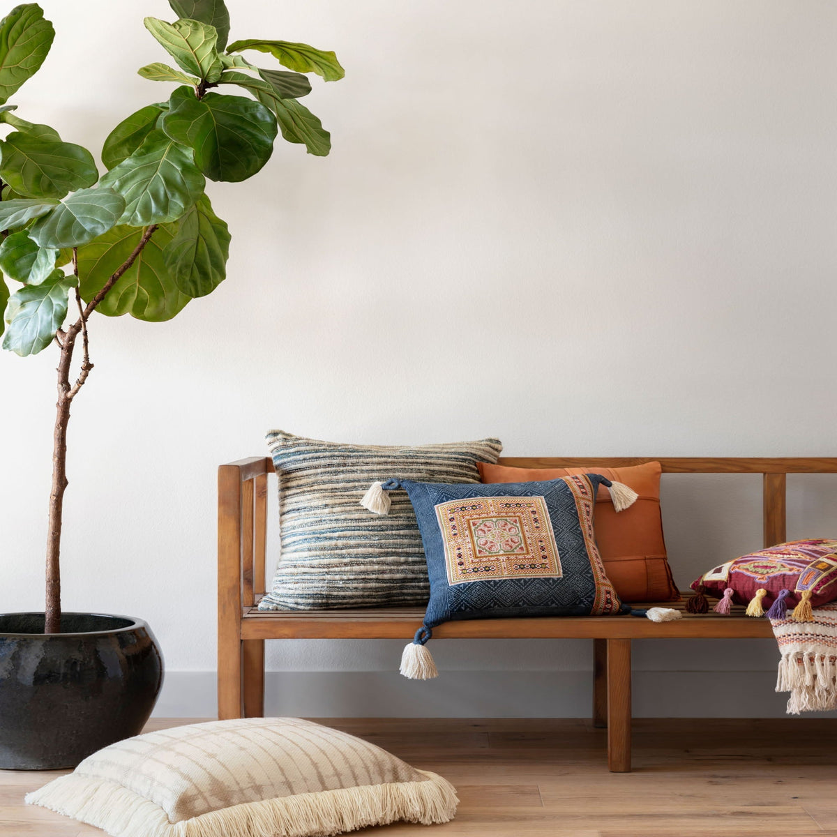 Multi-color woven throw pillow with tassels, shown on a sofa