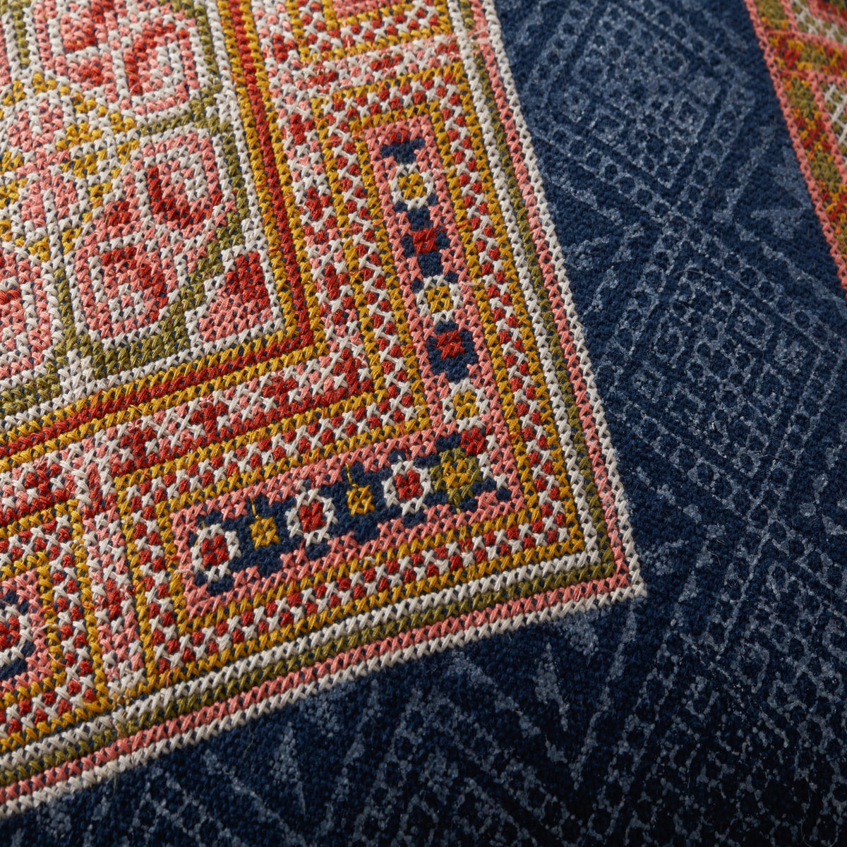 Multicolor geometric pillow fabric close-up with navy base and woven texture