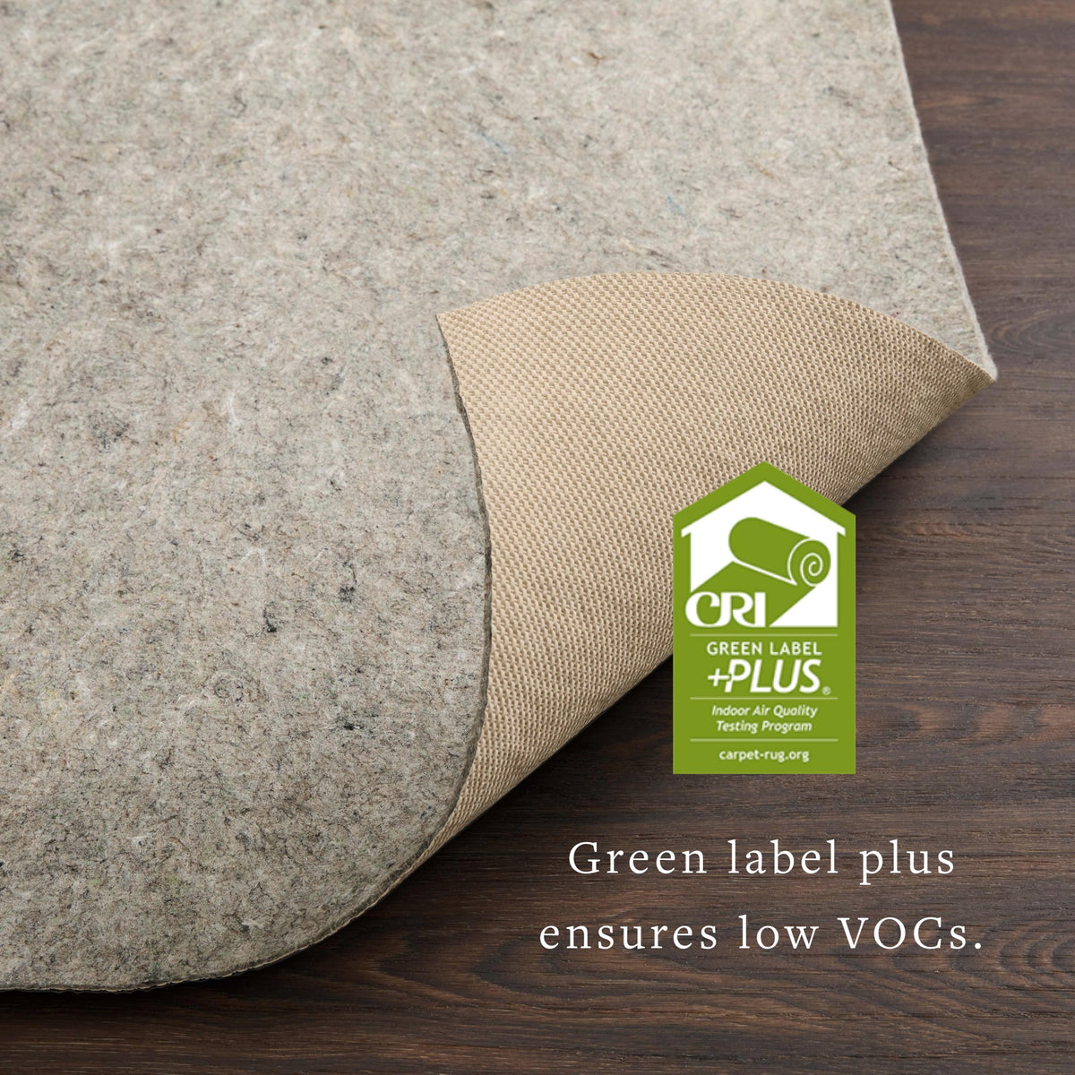 Grey felt rug pad corner with tan textured backing on dark wood floor