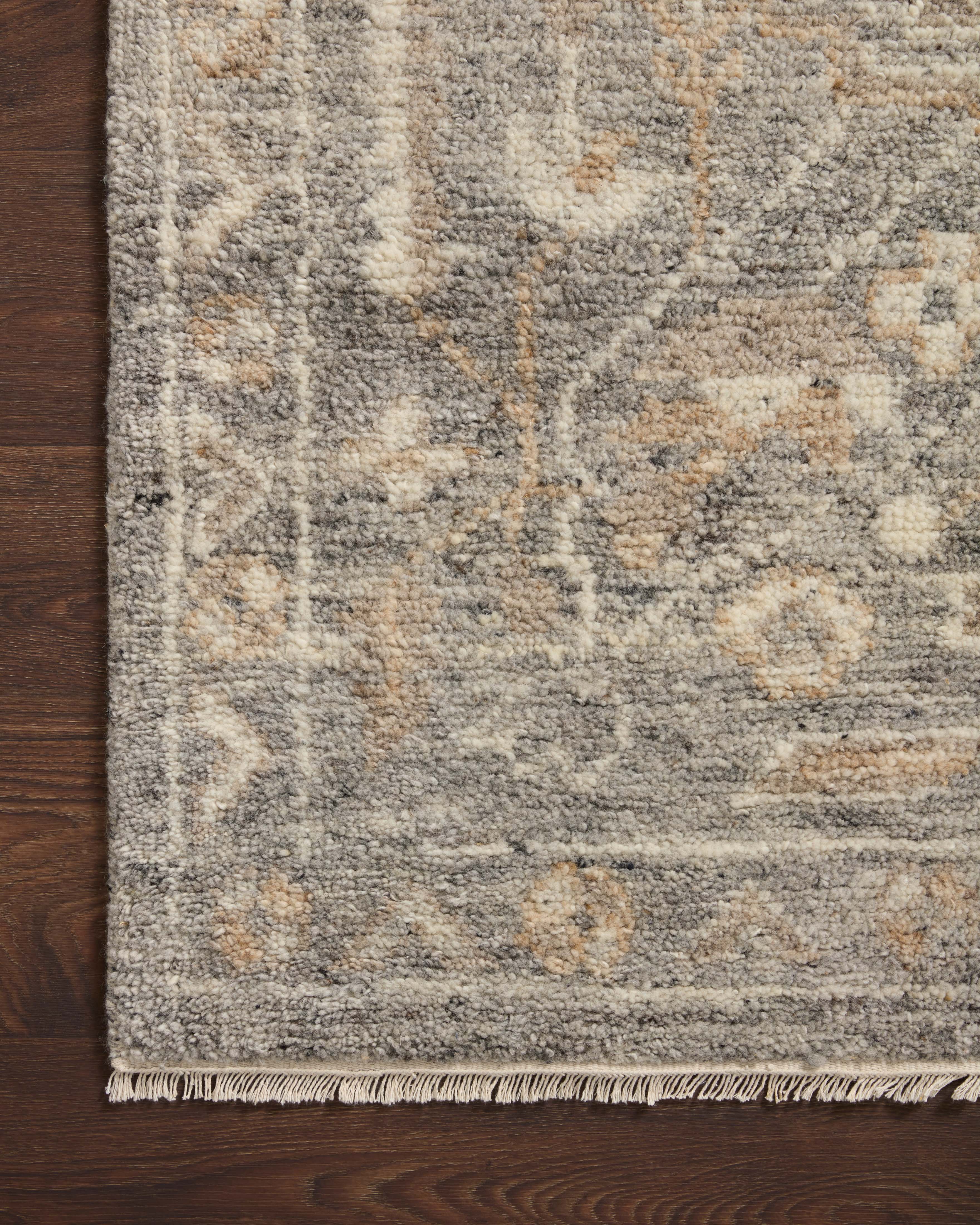 Gray-brown rug corner with textured wool pile, subtle motifs, and short fringe