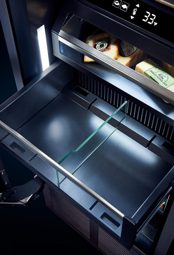 Built-in upright refrigerator interior with empty glass shelves and vented base