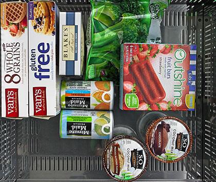 Refrigerator drawer interior with wire shelf, vent grille, and stocked food containers