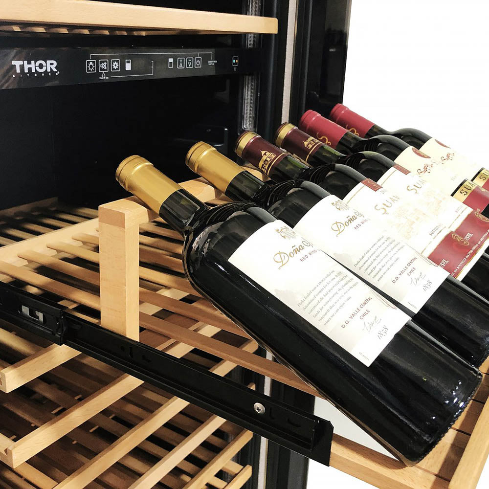 Wine bottles on wooden shelves inside a freestanding wine cooler with black interior