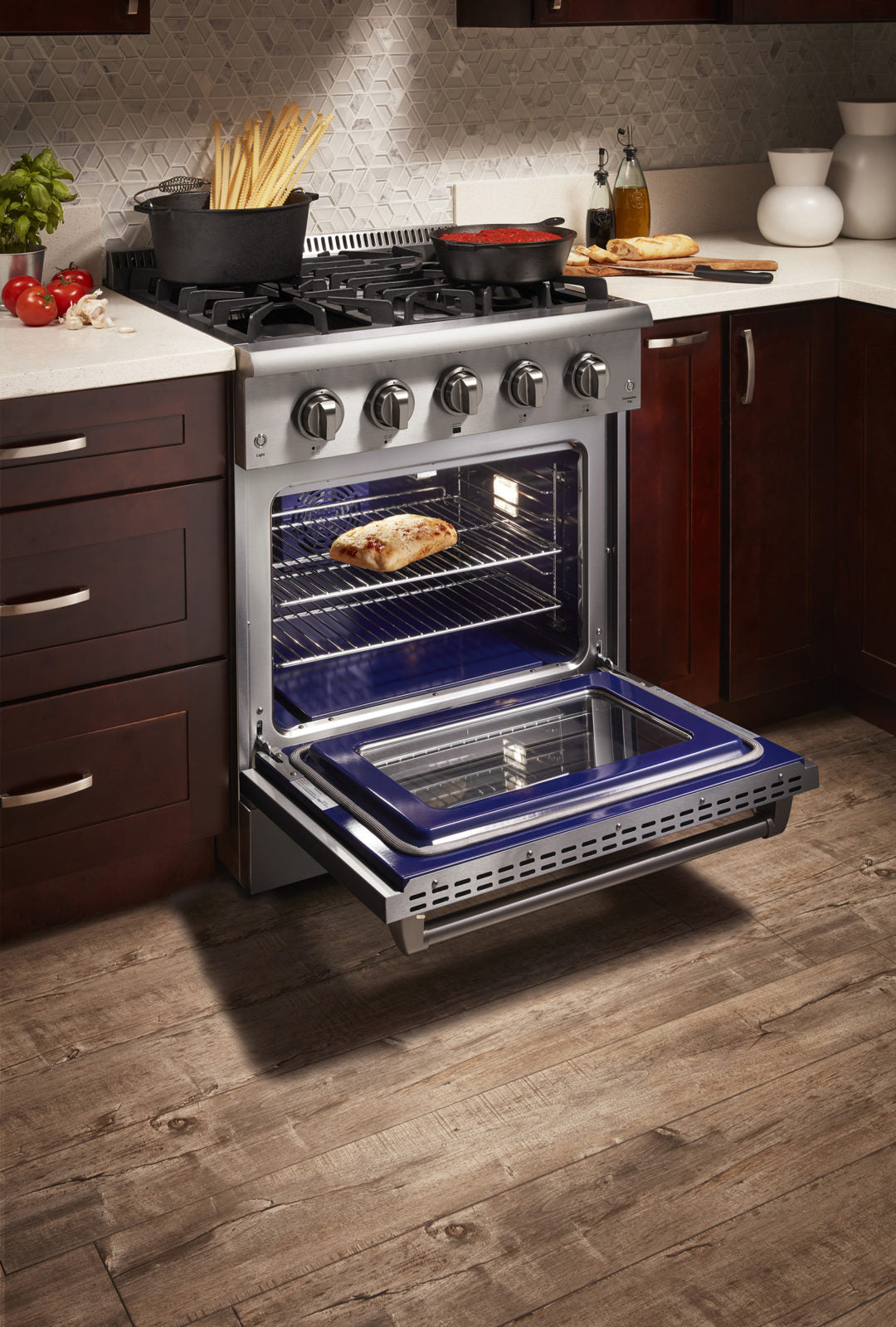 Stainless steel dual fuel range with oven door open showing interior racks and burner grates