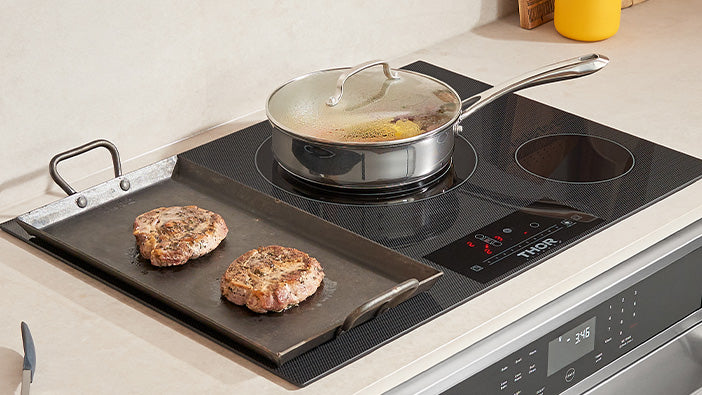 Thor black electric cooktop with two heating zones and control strip beside pan