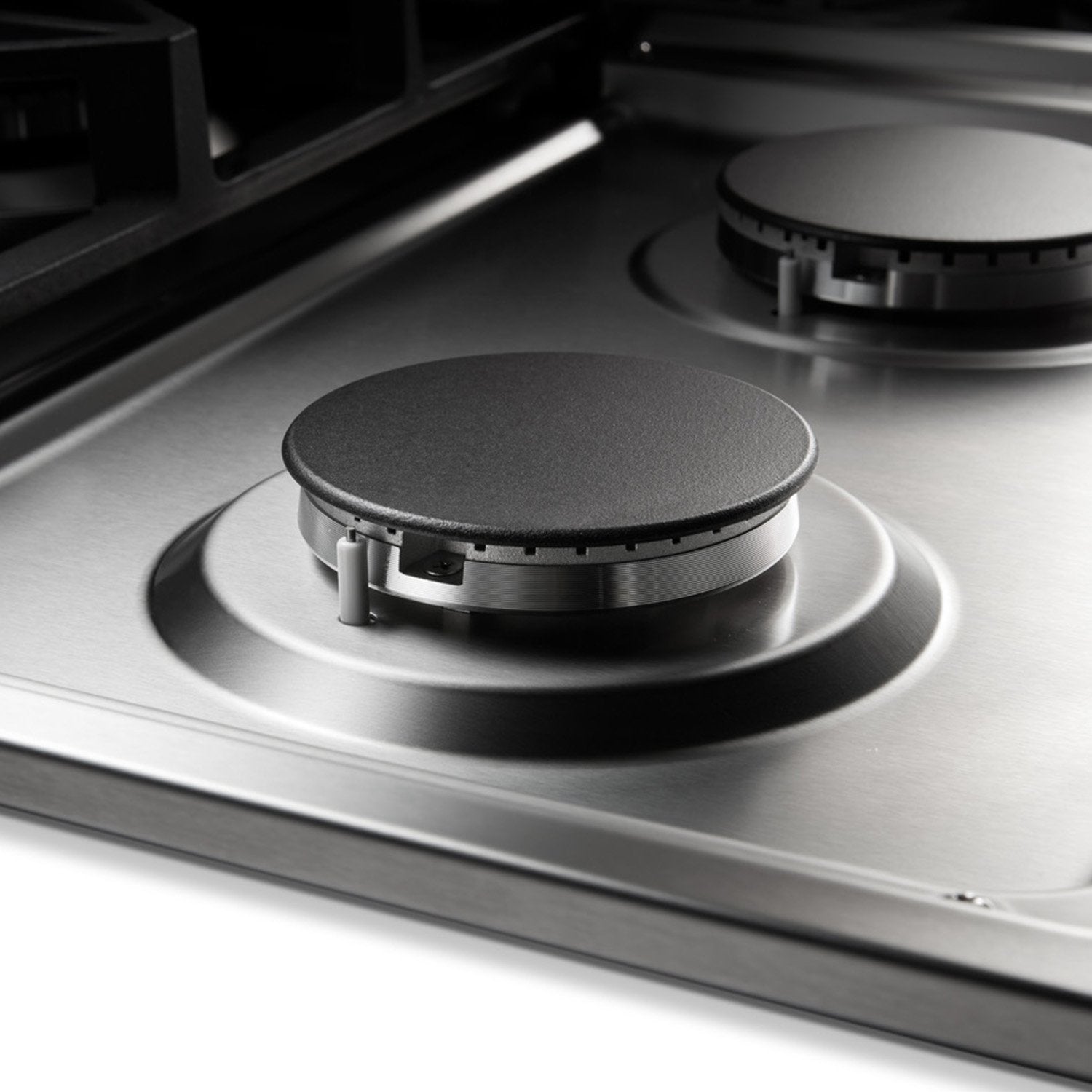 Close-up of circular gas burner on stainless steel cooktop with black control ring