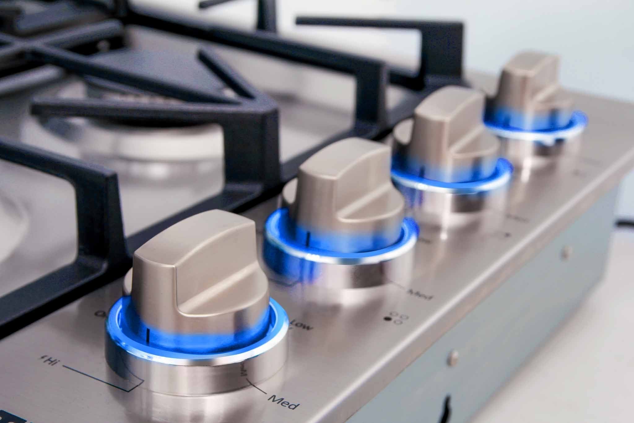 Metal burner knobs on stainless cooktop with blue indicator rings and OFF labels
