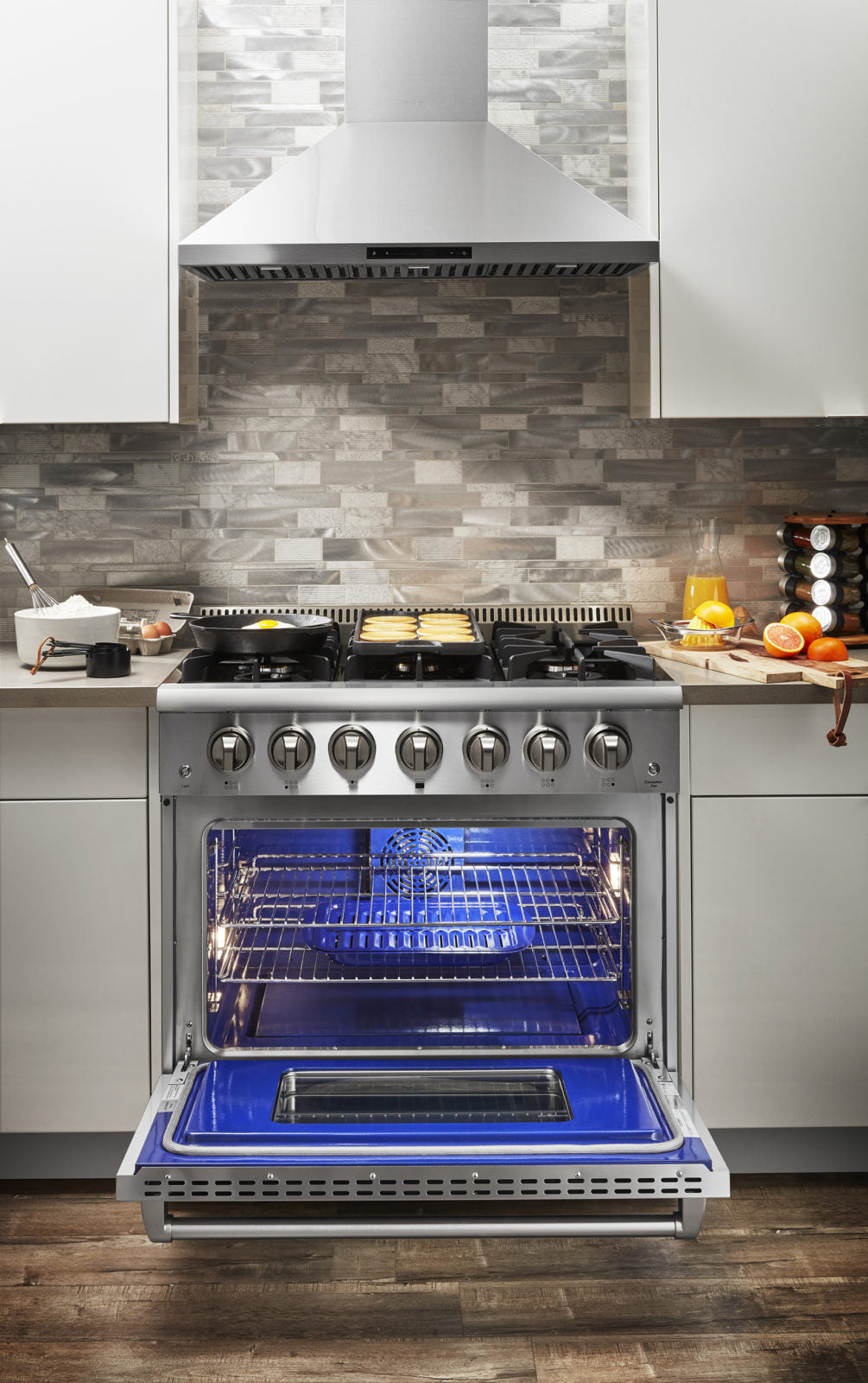 Stainless steel dual fuel range with open oven door showing blue interior racks