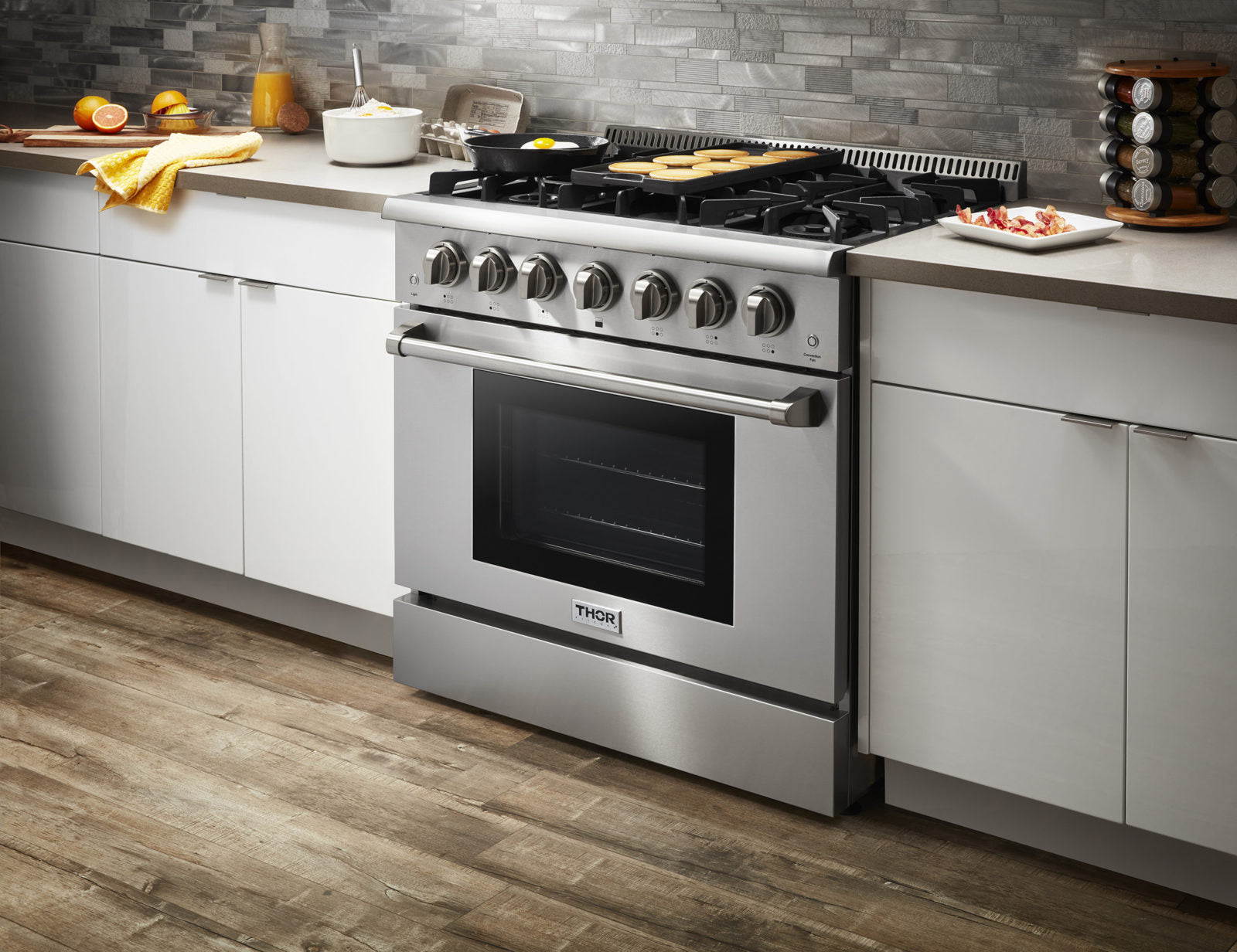 Stainless steel gas range with burner knobs and closed oven door, kitchen counter setup