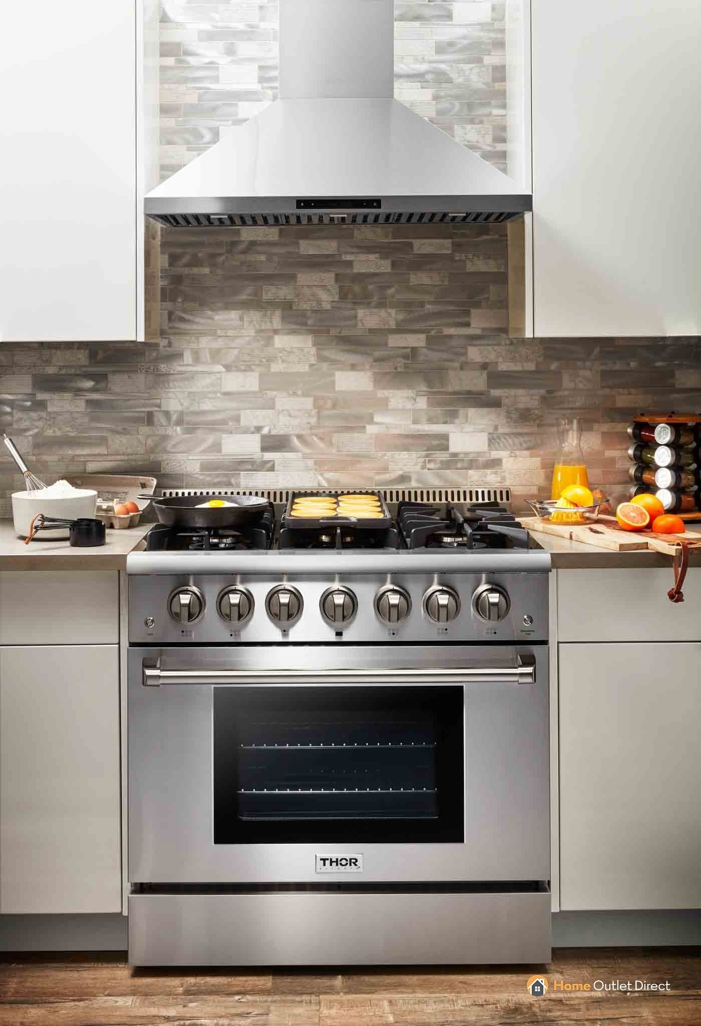 Stainless steel range with vent hood and open oven door in kitchen setting