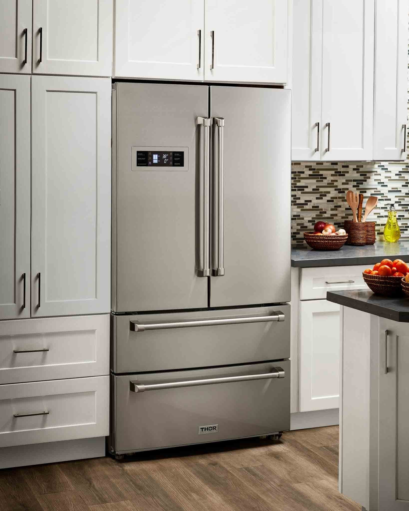 Stainless steel refrigerator in a home kitchen between gray cabinets