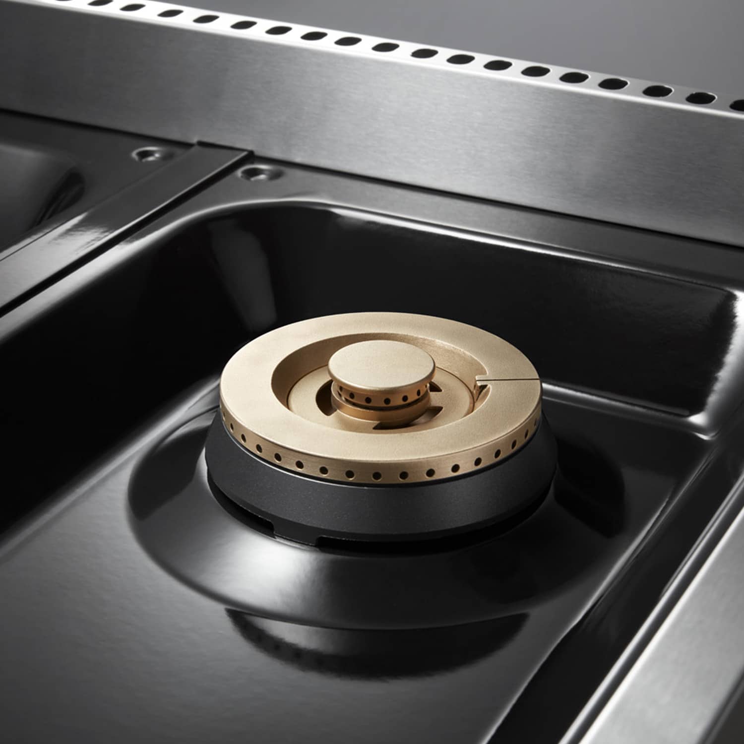 Stainless steel gas burner head with brass-toned cap and black grate support