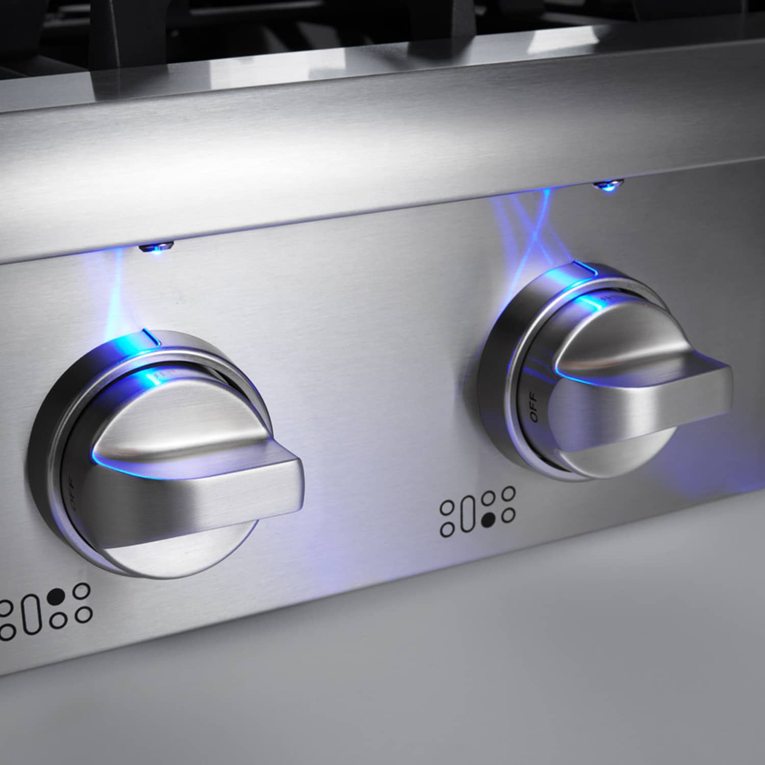 Stainless steel gas cooktop control knobs with blue indicator lights