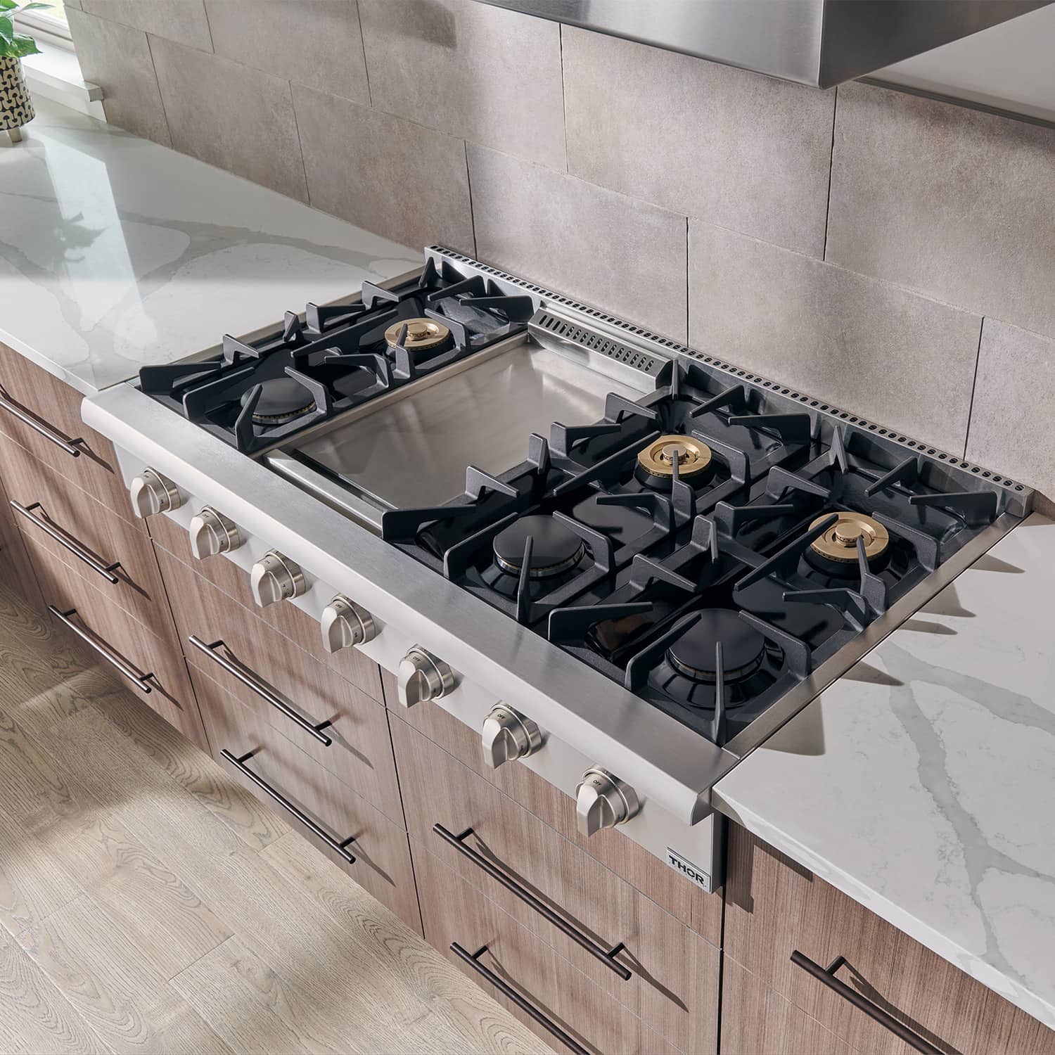 Stainless gas range cooktop with black burner grates and control knobs