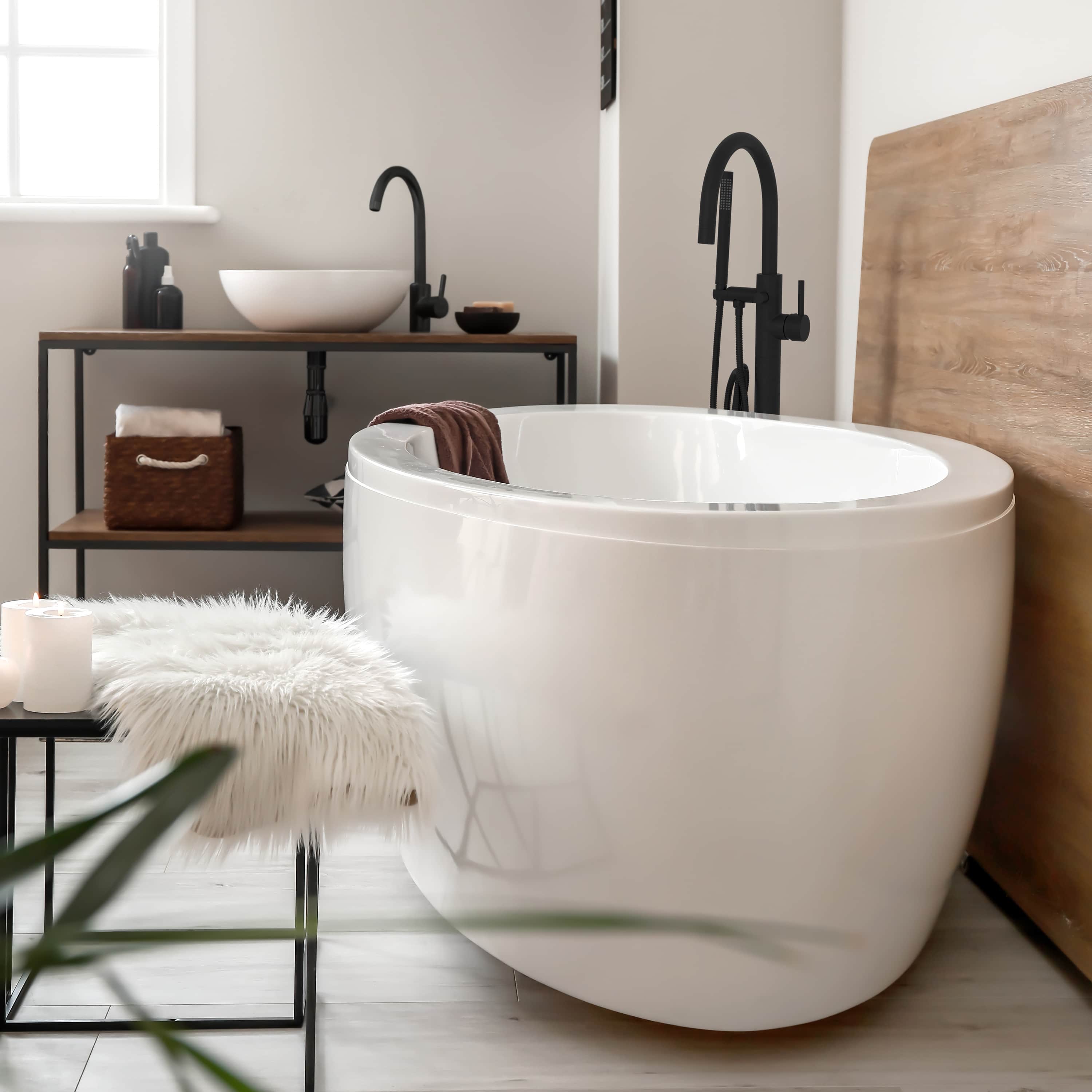 Matte black freestanding bath tub filler with curved spout and hand shower hose