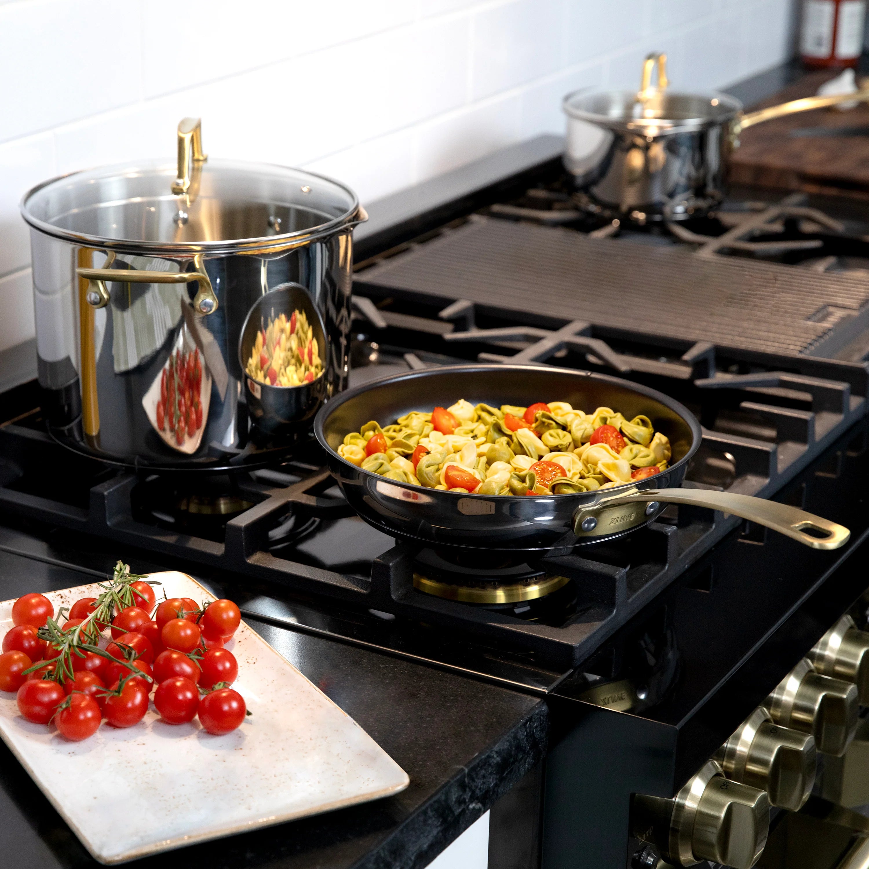 Stainless steel pot and black nonstick skillet cooking pasta on a gas range