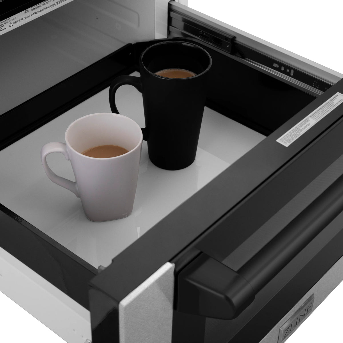 Open microwave drawer interior with two mugs and black turntable base