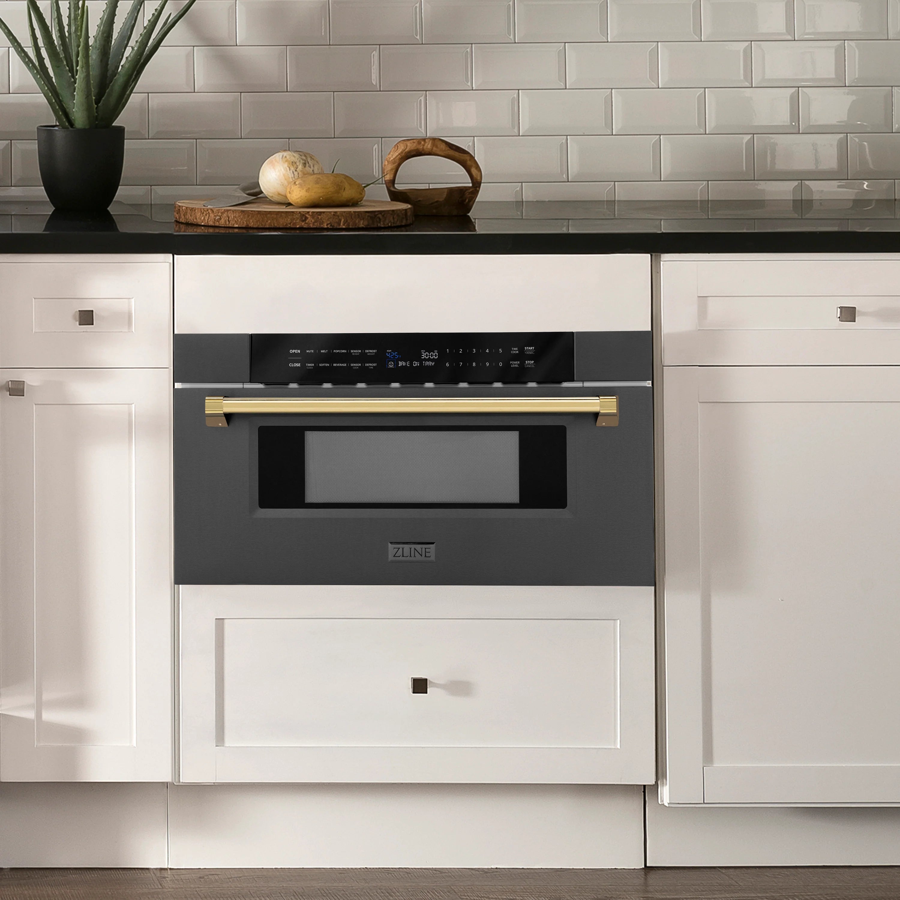 Black stainless built-in microwave drawer with gold handle accents in a kitchen