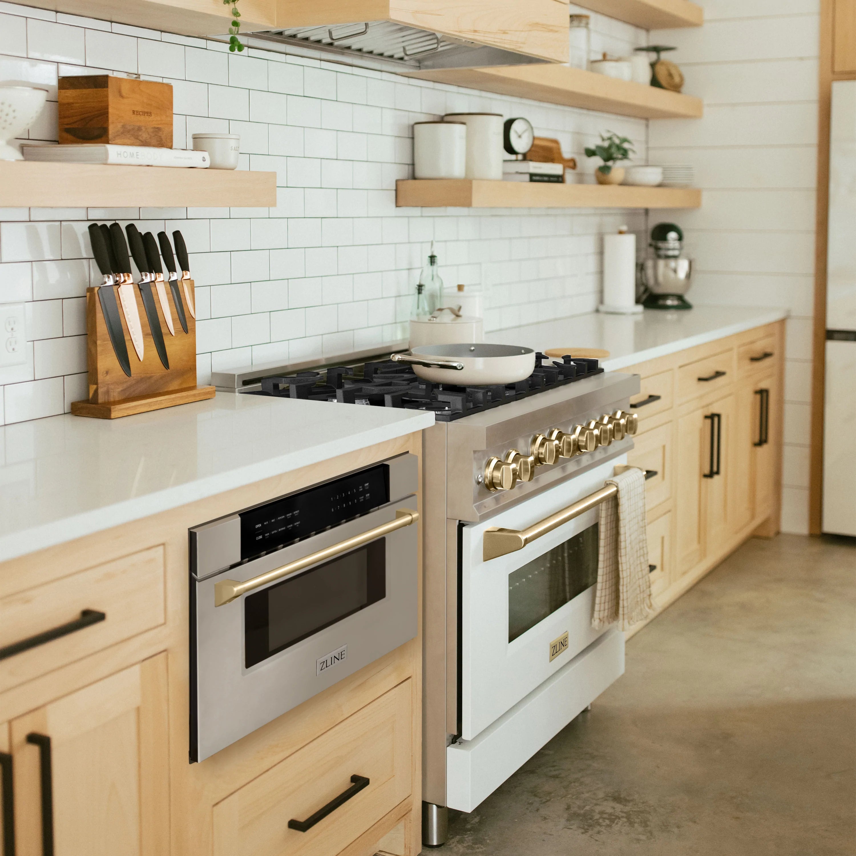 Built-in microwave drawer in cabinetry, stainless steel with gold trim accents