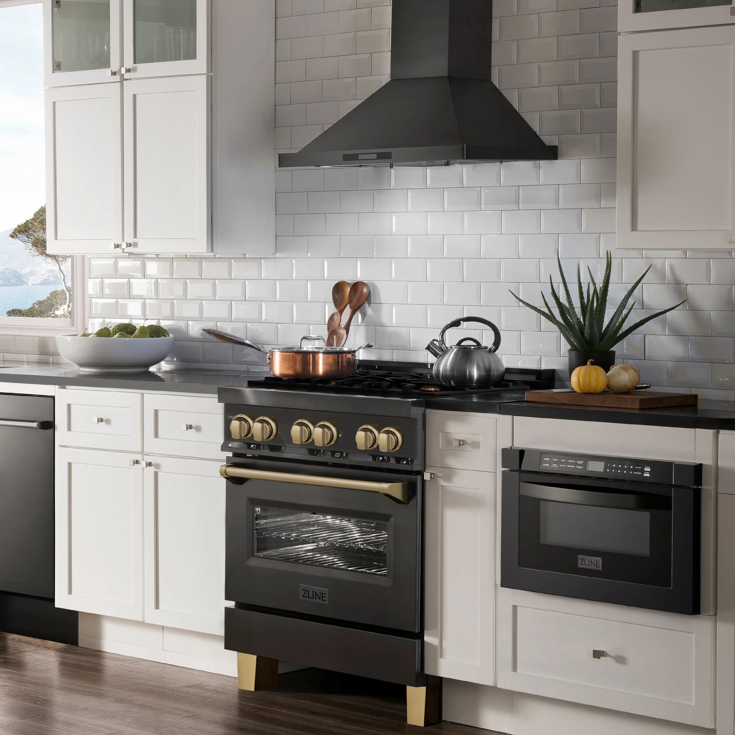 Black dual fuel range with champagne bronze knobs and wall-mounted range hood.