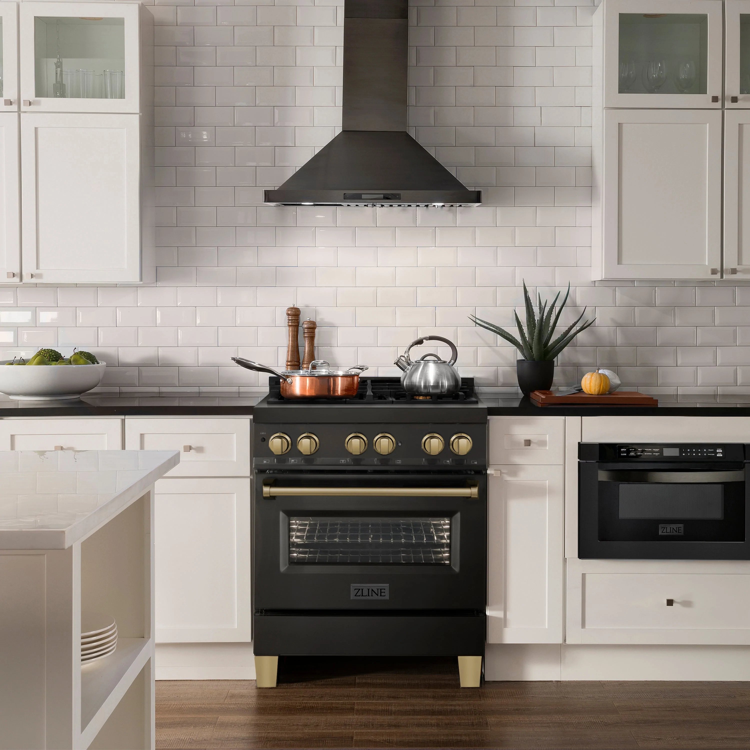 Black dual fuel range centered under a wall hood with champagne bronze control knobs