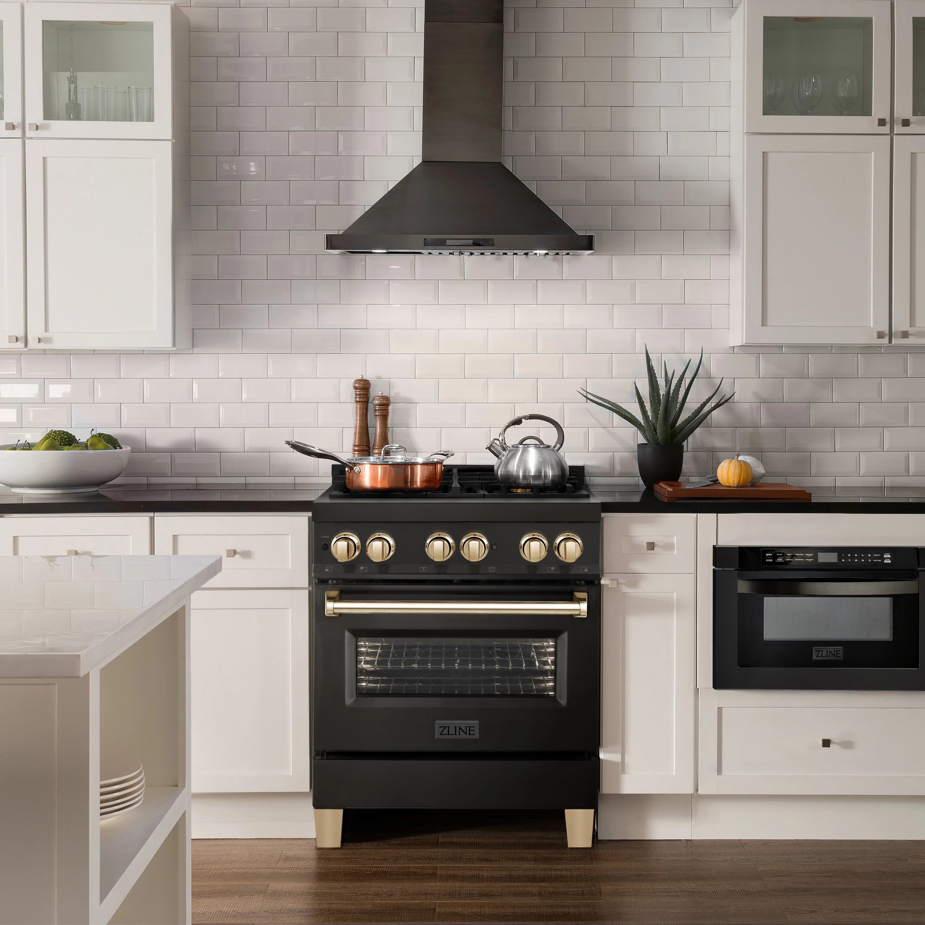Black dual fuel range with gold knobs and wall-mounted hood above